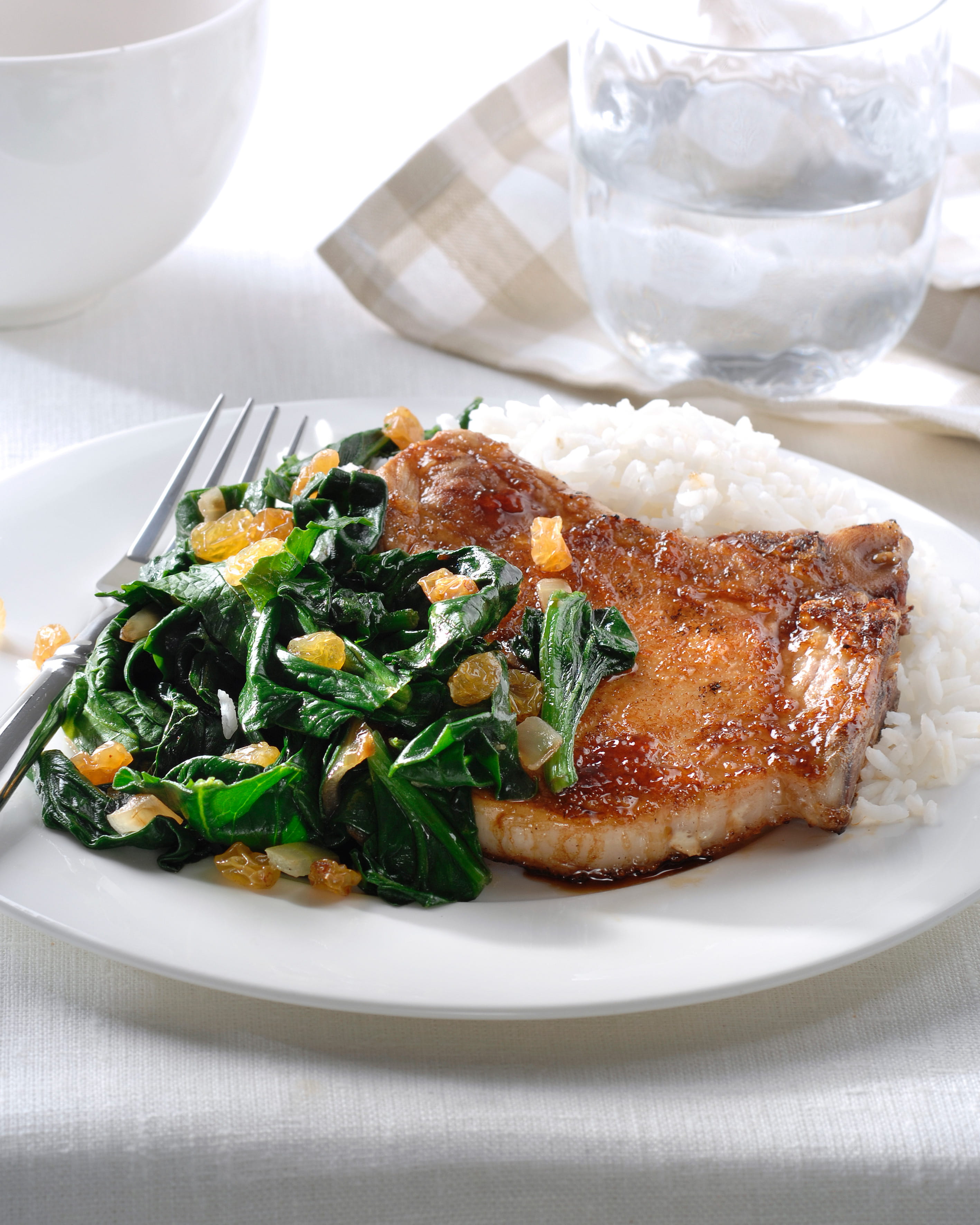 recipe image Zoet-pittige varkenskoteletjes en geroerbakte spinazie met rozijnen